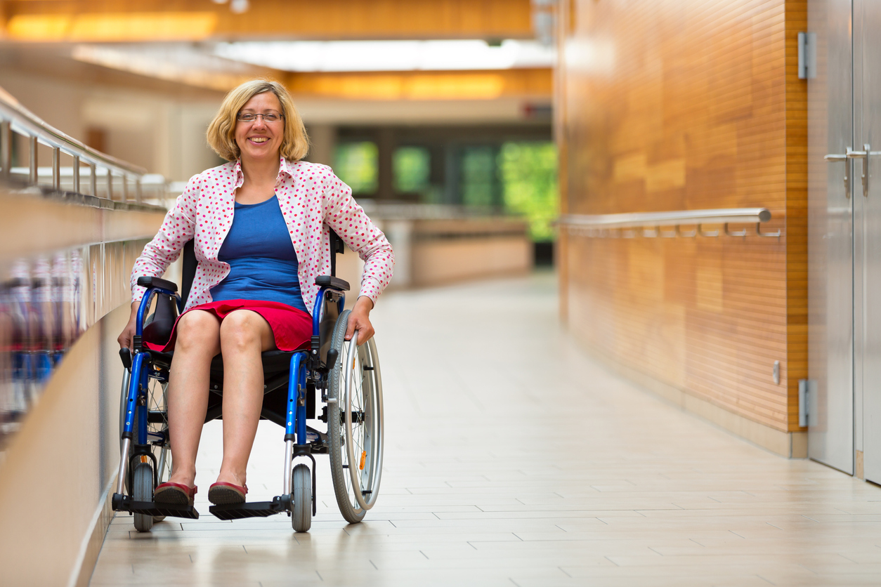 professional woman in wheel chair smiles while in a corporate setting