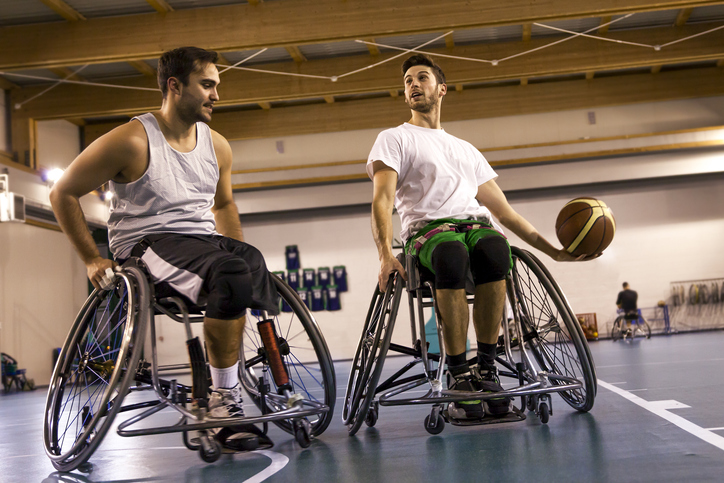 two men in wheelchairs playing basketball in a gym